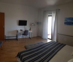 a bedroom with a bed and a desk and a television at Apartments & Rooms Tom in Medulin