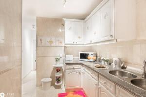 una cucina bianca con un lavello e un forno a microonde di Under A Fig Tree Apartment a Lisbona