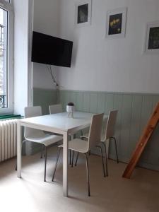 a white dining room table with chairs and a television at La Villa des Thermes in Le Mont-Dore