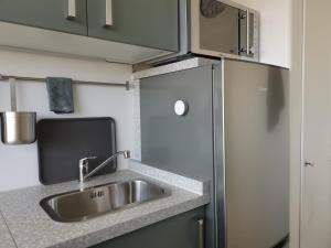 una cucina con lavello e frigorifero di City-Apartment Perle a Bremerhaven