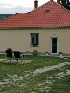 een tafel en stoelen voor een wit huis bij Livi Apartman in Szentantalfa