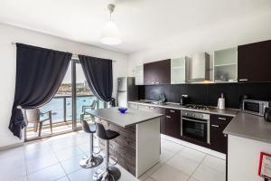 a kitchen with black cabinets and a view of the water at Z4 - SEAFRONT apartment in St. Paul's Bay