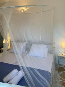 um quarto com uma cama de dossel e almofadas brancas em Keramoto Cottage - Kythoikies holiday houses em Kýthira