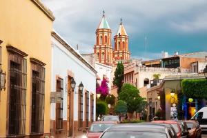 a city street with cars parked in front of a church at Casa Aspeytia Hotel Boutique in Querétaro