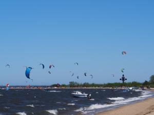 a group of people flying kites in the water at a beach at Apartament Fala in Mechelinki