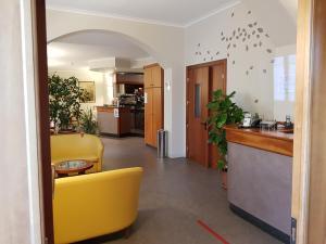 un vestíbulo con una silla amarilla y una cocina en Hotel Cavour, en Asti