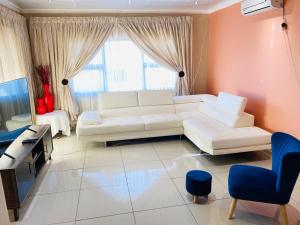 a living room with a white couch and a tv at River Valley Guest House in Butterworth