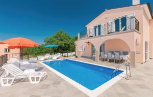 a swimming pool with chairs and an umbrella and a house at villa dijana in Viskovići