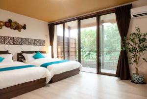 1 dormitorio con 2 camas y ventana grande en Jin Jin House -SEVEN Hotels and Resorts-, en Nakijin