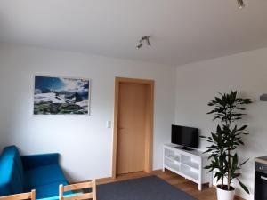 un soggiorno con sedia blu e TV di Appartement PIA a Schönberg im Stubaital