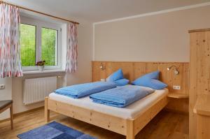sypialnia z drewnianym łóżkiem z niebieskimi poduszkami w obiekcie Apartments Kirchebnerhof w mieście Oetz