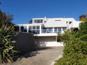 uma casa branca com uma cerca à frente. em BEACH FRONT:Palms-on-the-beach.KAITERITERI. em Kaiteriteri