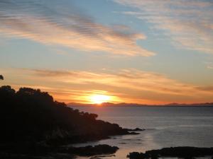 a sunset over a body of water at BEACH FRONT:Palms-on-the-beach.KAITERITERI. in Kaiteriteri