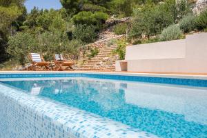 a blue swimming pool with two chairs and stairs at Villa Brac with pool Bol in Bol