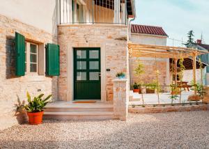 Casa Nuoneti في Žminj: باب أخضر على منزل من الطوب مع مصاريع خضراء