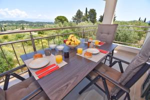 een houten tafel met een fruitschaal op een balkon bij Villa Caesar in Ágios Ioánnis