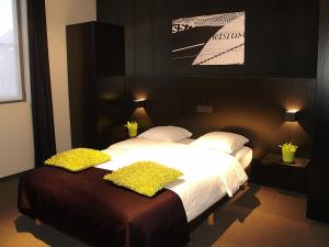ein Schlafzimmer mit einem großen Bett mit weißer Bettwäsche und gelben Kissen in der Unterkunft Hotel Florent in Lier