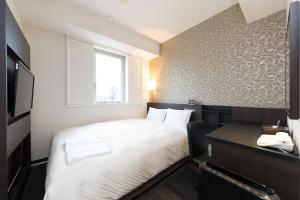 a small bedroom with a white bed and a window at Sanco Inn Numazu Ekimae in Numazu