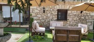 a patio with chairs and an umbrella in front of a stone building at Casa Rural Pedraza in Pedraza-Segovia