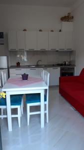 a kitchen with a white table and chairs and a red couch at Villa Fredi in Orikum +42 photos