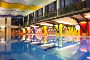 una piscina con sedie colorate in un edificio di Alpin & See Resort a Zell am See