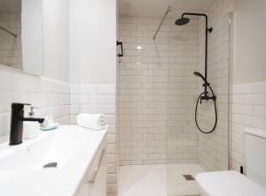 uma casa de banho branca com um chuveiro e um lavatório. em Latidos de Sevilla I - Deluxe con piscina em Sevilha