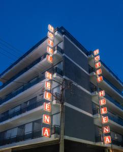 un bâtiment avec des panneaux de néon sur son côté dans l'établissement Hotel Elena, à Larissa