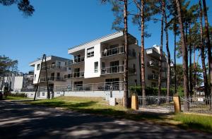 un edificio de apartamentos blanco con árboles delante de él en Apartament IKAR przy morzu w kompleksie LAOLA z ogródkiem en Pobierowo