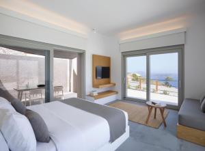 a bedroom with a bed and a tv and a couch at Melidonia Suites in Akrotiri