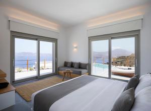 a bedroom with a large bed and large windows at Melidonia Suites in Akrotiri