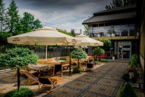 un patio al aire libre con mesas, sillas y sombrillas en Restauracja Sonata, en Zwierzyniec