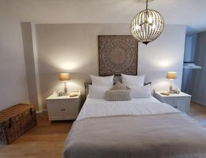 um quarto com uma cama grande, 2 mesas de cabeceira e um lustre. em Quedlinburg Marktplatz-Suites em Quedlinburg