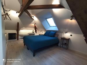 1 dormitorio con 1 cama azul en el ático en Chambre chez l'habitant Les Aubes du Vexin, en Nucourt