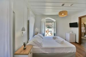 Un dormitorio blanco con una cama grande y una mesa. en Onar Hydra, en Hydra