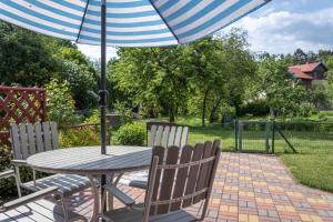 a table and chairs with an umbrella on a patio at Cozy one room apartment with yard in Juodkrantė