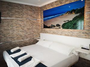 a bedroom with a white bed and a brick wall at Hostal Costa De La Luz in Conil de la Frontera