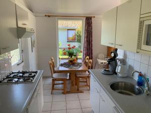 a kitchen with a sink and a table with a stove at Bungalow36 - Petten in Petten