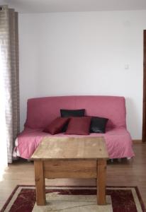 a pink couch with a wooden table in a room at Apartamenty u Majki in Frydman