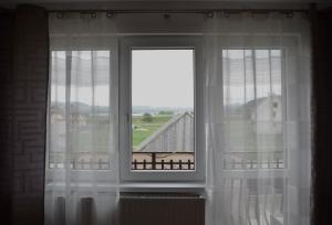 a window with white curtains and a view of a building at Apartamenty u Majki in Frydman