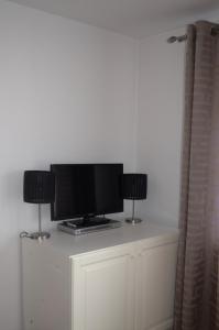 un televisor en la parte superior de un armario blanco con dos lámparas en Apartamenty u Majki, en Frydman