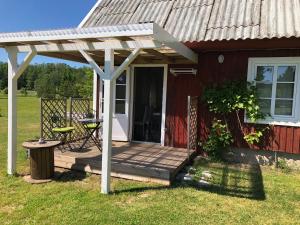 a porch of a red house with a wooden deck at Sarapuu puhkemaja in Hullo