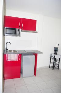 a kitchen with red cabinets and a sink at Résidence d'Artagnan in Montargis