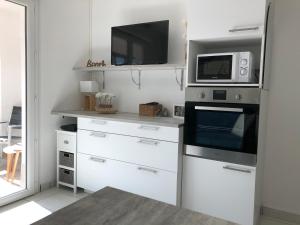 a white kitchen with a microwave and a stove at Cabourg plage à 200m plage in Cabourg
