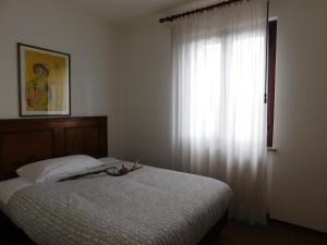 a bedroom with a bed and a window with white curtains at Albergo Alla Posta in Anduins
