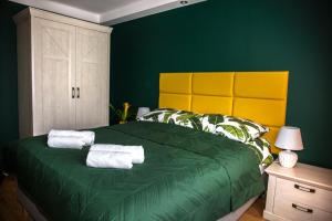 a green bedroom with a large bed with towels on it at Apartament Panorama 2 18 in Polańczyk