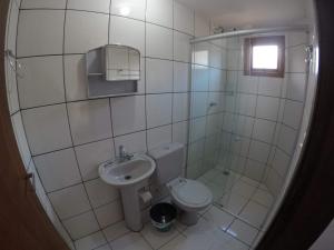 een witte badkamer met een toilet en een wastafel bij Pousada da Montanha in Campos do Jordão