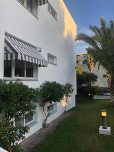 a white building with a striped awning next to a yard at Soltroia Housefeelings in Troia