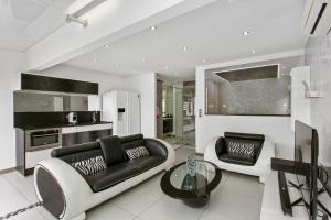 a living room with a black couch and a table at Village Naturiste - La Villa Tentation Port Nature Luxe in Cap d'Agde