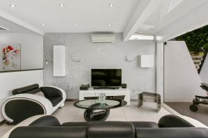 a living room with black and white furniture and a television at Village Naturiste - La Villa Tentation Port Nature Luxe in Cap d'Agde