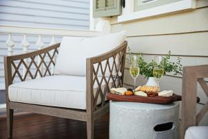 une terrasse couverte avec une chaise et un plateau de nourriture et des verres de vin dans l'établissement 86 Cannon Historic Inn - Adults Only, à Charleston